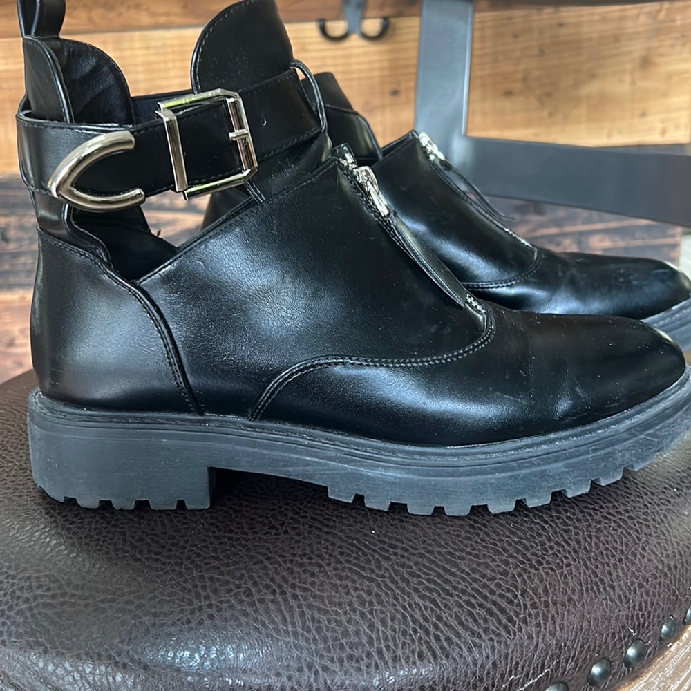 Black combat style boots with front zipper. Open sides and ankle buckle